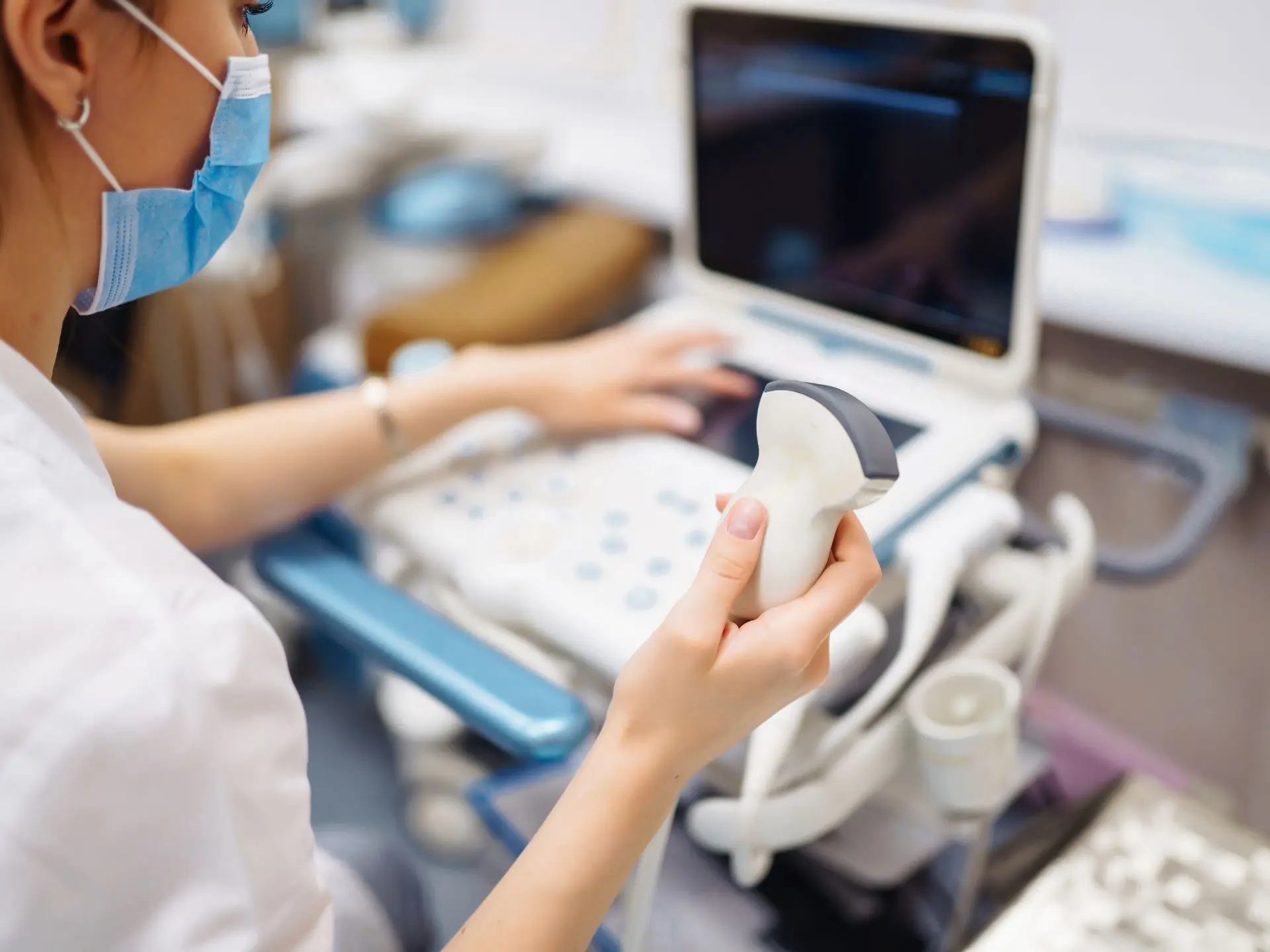 Reparatur Ultraschall Sonografie Gerät niedergelassene Ärzte Graz. Frauenhand mit Sonde von Ultraschall-Gerät vor dem Monitor.